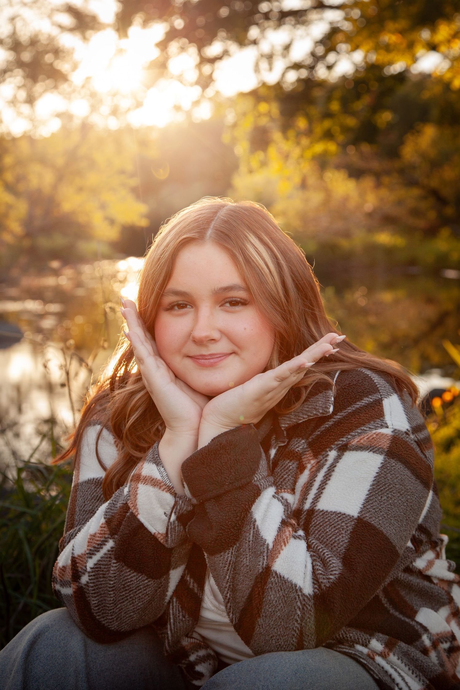 A smiling portrait outdoors, with hands framing the face.